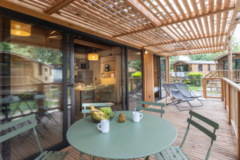 Terraza de madera con sillas y pérgola en el Chalet Columbia, Camping de l'Ill - Colmar, Francia.