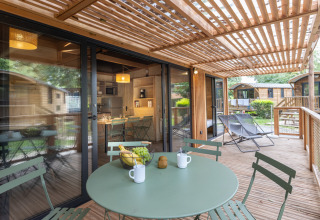 Terraza de madera con sillas y pérgola en el Chalet Columbia, Camping de l'Ill - Colmar, Francia.