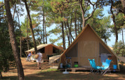 Tiendas safari en el bosque de Huttopia Noirmoutier, Francia, con sillas al aire libre y ambiente familiar.