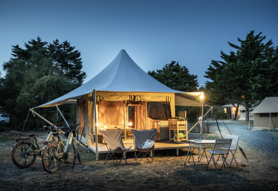 Panama Safari-Zelt mit beleuchtetem Eingang, Fahrrädern und Sitzbereich am Abend im Camp.