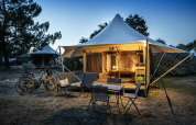 Safari-Zelt Panama Tent bei Huttopia Ars-en-Ré in Frankreich mit Beleuchtung, Stühlen und Fahrrädern draußen.