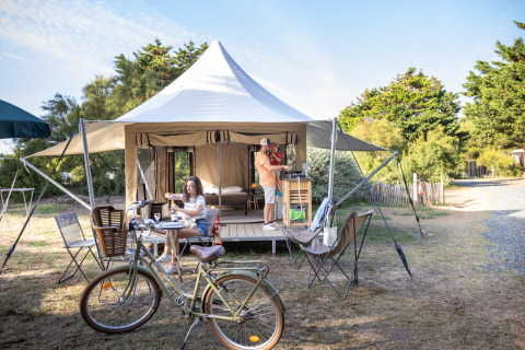 Glamping en la tienda Panama en Huttopia Ars-en-Ré, Francia, con personas disfrutando y una bicicleta afuera.