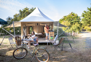 Glamping at the Panama Tent at Huttopia Ars-en-Ré in France, featuring people relaxing and a bicycle outside.