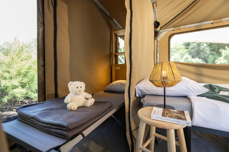 Interior of the Panama Tent at Huttopia Ars-en-Ré in France featuring beds, a lamp, and a teddy bear.