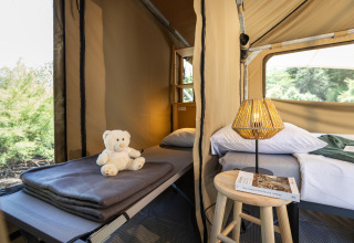Interno della tenda Panama a Huttopia Ars-en-Ré in Francia con letti, abat-jour e orsetto di peluche.
