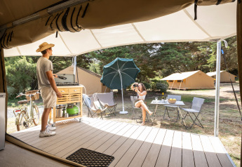 Coppia che si rilassa davanti a una tenda safari Panama a Huttopia Ars-en-Ré, Francia, in campeggio.