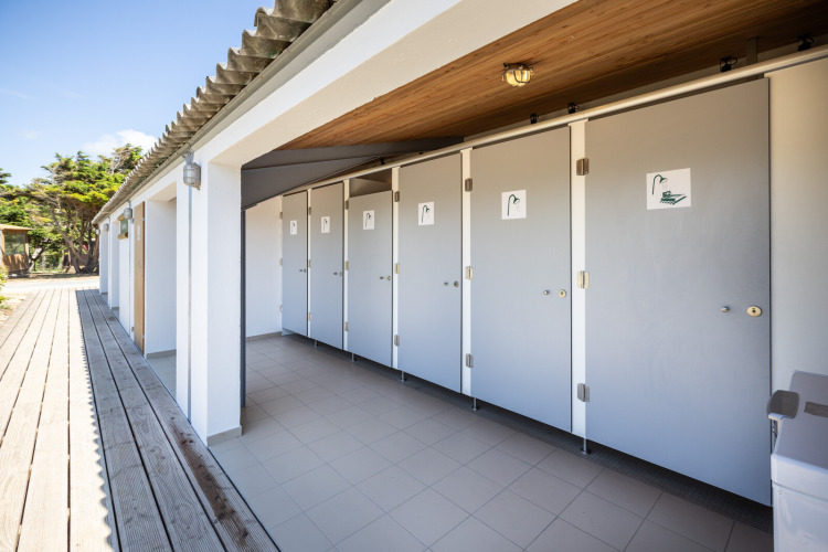 Outdoor shower facilities beside the Panama Tent at Huttopia Ars-en-Ré, France, captured in daylight.