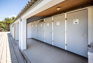 Outdoor shower facilities beside the Panama Tent at Huttopia Ars-en-Ré, France, captured in daylight.