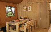 Sala da pranzo in una tenda safari al Camping Si-Es-An nei Paesi Bassi, con mobili in legno chiaro.