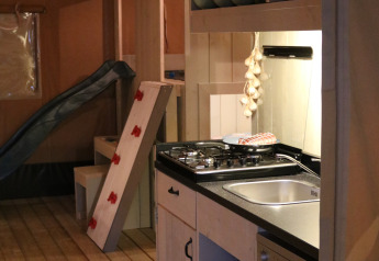 Interior de una tienda safari en Camping Si-Es-An, Países Bajos, con cocina y zona de juegos.