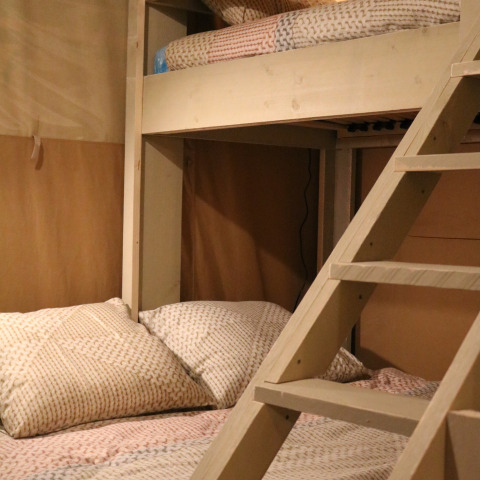 Vista interior de una tienda safari con litera y ropa de cama acogedora en Camping Si-Es-An, Países Bajos.