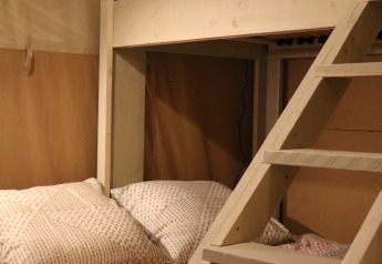 Vista interior de una tienda safari con litera y ropa de cama acogedora en Camping Si-Es-An, Países Bajos.