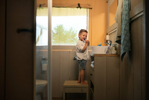 Petit garçon se brossant les dents dans la salle de bain d'une tente safari au Camping Si-Es-An, Pays-Bas.