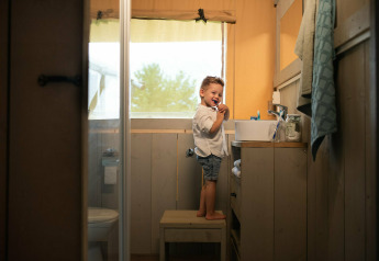 Niño pequeño cepillándose los dientes en el baño de una tienda safari en Camping Si-Es-An, Países Bajos.