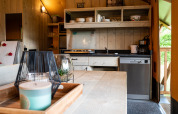 Interieur van een safaritentkeuken bij Camping Si-Es-An met houten tafel, servies en vaatwasser.