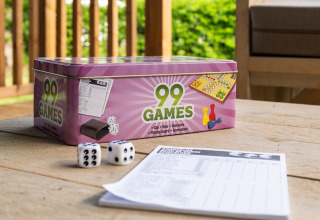 Spielebox mit 99 Spielen, Würfeln und Spielblock auf einem Tisch vor einem Safarizelt auf Camping Si-Es-An.