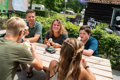 Una familia disfruta de helado sentada en una mesa al aire libre en una tienda safari en los Países Bajos.