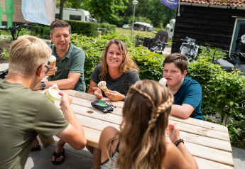 Una famiglia gusta il gelato seduta a un tavolo all'aperto presso una tenda safari nei Paesi Bassi.