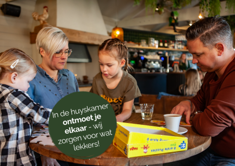 Gezin speelt spelletjes in Heydehuis tiny house bij Sandberghe, Nederland, gezellige huiskamersfeer.