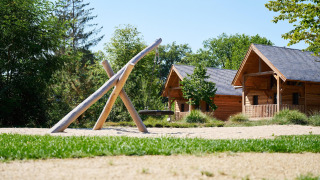 Foto van Heydehuis + Jacuzzi bij Sandberghe in Nederland met houten lodges en speeltoestel.