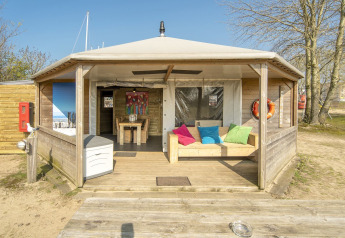 Udendørs udsigt til Dune house lodge ved Marina Parcs Almere, Holland, med farverige puder på en bænk.