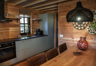 Modern houten keuken- en eetgedeelte in Heydehuis + Jacuzzi lodge, Sandberghe, Nederland, veel daglicht.