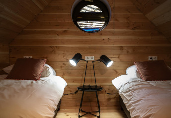 Dormitorio acogedor en Heydehuis + Jacuzzi en Sandberghe, Países Bajos, con dos camas y lámparas modernas.