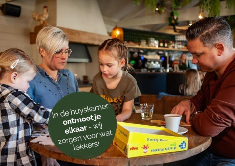 Familia comparte un rompecabezas en la sala común del glamping Heydehuis + Jacuzzi.