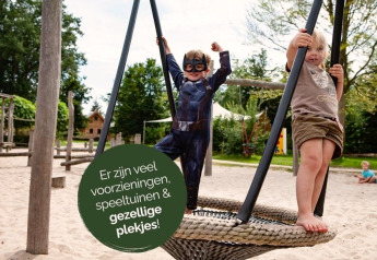 Zwei Kinder spielen auf einem Spielplatz mit Sand und Schaukeln bei Heydehuis + Jacuzzi Glamping.