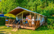Niños y una mascota de oso en la terraza de una tienda safari en Lodgetent Beaufort, Holiday Park Walsdorf, Luxemburgo.