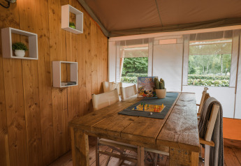 Interior de la tienda safari Lodgetent Beaufort en Beter Uit Holiday Park Walsdorf, Luxemburgo, con mesa rústica.