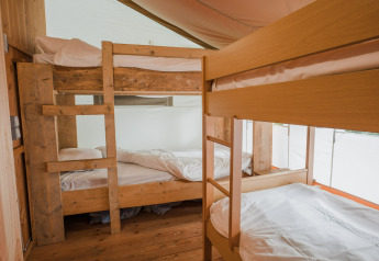 Interior de la tienda Lodgetent Beaufort con dos literas de madera en Beter Uit Holiday Park Walsdorf, Luxemburgo.