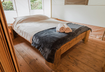 Vista interior de la tienda Lodgetent Beaufort en Beter Uit Holiday Park Walsdorf, Luxemburgo, con cama doble.