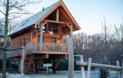 Treehouse on stilts with balcony and stairs at Sandberghe in the Netherlands, surrounded by natural scenery.