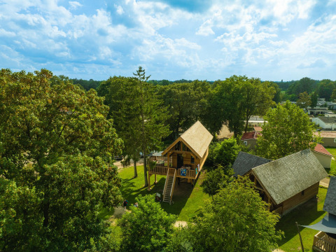 Aerial view of Heydehuis + Jacuzzi treehouse at Sandberghe in the Netherlands, surrounded by lush greenery.
