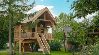 Boomhuis Heydehuis + Jacuzzi bij Sandberghe in Nederland, met houten terras en groene omgeving.