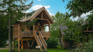 Træhus Heydehuis + Jacuzzi ved Sandberghe i Holland, omgivet af grønt, med trætrappe og terrasse.