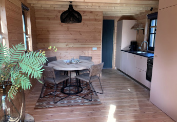 Gemütliches Baumhaus-Interieur mit Essbereich und Küche im Heydehuis + Jacuzzi bei Sandberghe, Niederlande.