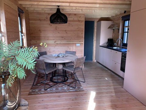 Moderne boomhut met eettafel, keuken en grote ramen in Heydehuis + Jacuzzi bij Sandberghe, Nederland.