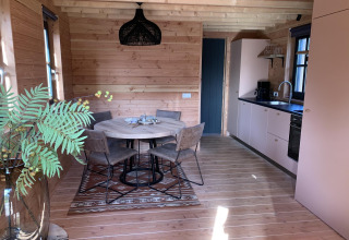 Gemütliches Baumhaus-Interieur mit Essbereich und Küche im Heydehuis + Jacuzzi bei Sandberghe, Niederlande.