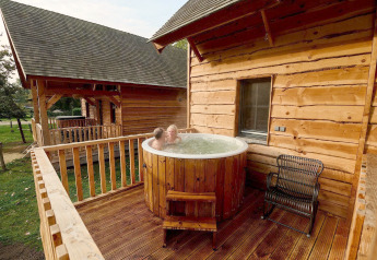 Zwei Personen entspannen im Jacuzzi auf der Terrasse eines Baumhauses im Heydehuis bei Sandberghe, Niederlande.