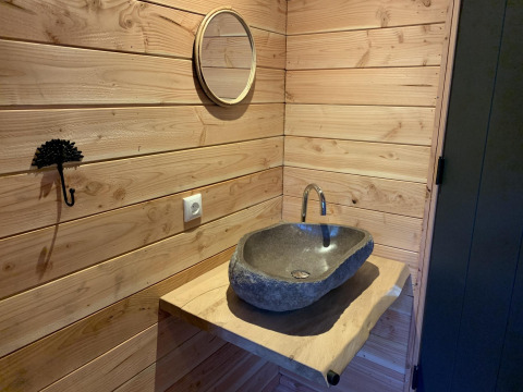 Lavabo de piedra y encimera de madera con espejo en una casa del árbol en Sandberghe, Países Bajos.