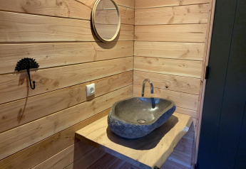 Steinwaschbecken mit Holzarbeitsplatte und Spiegel in einem Baumhaus bei Sandberghe, Niederlande.