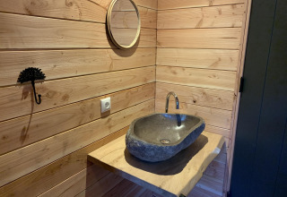 Lavabo de piedra y encimera de madera con espejo en una casa del árbol en Sandberghe, Países Bajos.