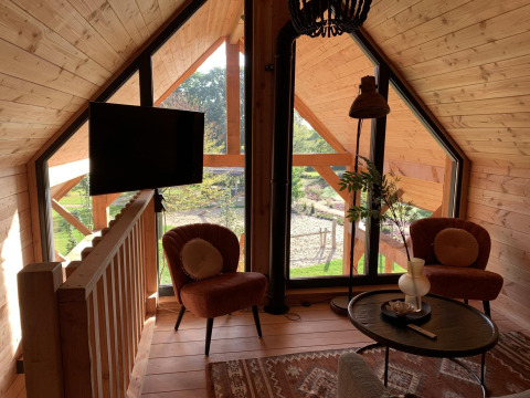 Lys stue i træhus Heydehuis + Jacuzzi ved Sandberghe, Nederlandene, med store vinduer og hyggelig indretning.