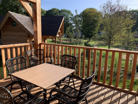 Terraza de madera con mesa y sillas vista al jardín en Heydehuis + Jacuzzi, Sandberghe, Países Bajos.
