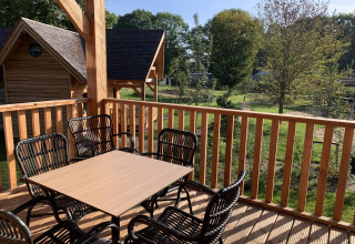 Terraza de madera con mesa y sillas vista al jardín en Heydehuis + Jacuzzi, Sandberghe, Países Bajos.