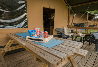 Mesa de madera al aire libre con aperitivos frente a una tienda safari en Beter Uit Holiday Park Walsdorf, Luxemburgo.