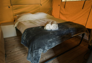 Interior de la tienda safari La Rochette con cama doble y toallas, Beter Uit Holiday Park Walsdorf, Luxemburgo.