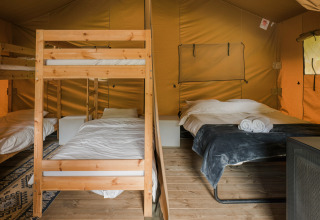 Interior de la tienda Safari La Rochette con literas y cama doble en Beter Uit Holiday Park Walsdorf, Luxemburgo.